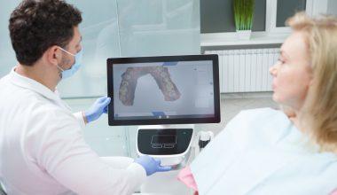 # Cum simplifică 3DentaSoft relația dintre medicul stomatolog și tehnicianul dentar Pe colțul unui birou de recepție stă un plic maro cu numele pacientului scris de mână. Înăuntru, o amprentă de silicon, o fișă completată în grabă și un bilețel cu nuanța aleasă. Plicul așteaptă curierul, curierul așteaptă traficul, iar tehnicianul dentar așteaptă să vadă ce a primit. Cam așa a arătat, ani la rând, colaborarea dintre un cabinet stomatologic și un laborator dentar. Doi profesioniști care lucrează la același pacient, uneori la câteva sute de kilometri distanță, care nu se văd niciodată la față și care comunică prin obiecte fizice și prin telefoane date între două consultații. Cele mai multe frustrări din protetică nu vin din lipsă de competență, ci din traducerea greșită a intenției dintr-un cap în altul. ## Ce se pierde de fapt între cabinet și laborator Un medic bun știe exact ce vrea. Problema apare când trebuie să pună asta pe hârtie, într-o rubrică de trei rânduri, la sfârșitul unei zile în care a avut unsprezece pacienți. Scrie "coroană zirconiu 26, A3", pune amprenta în plic și pleacă acasă convins că a spus tot. Tehnicianul deschide plicul a doua zi. Vede o amprentă cu o bulă de aer fix în zona pragului, o antagonistă turnată aproximativ și o nuanță care nu spune nimic despre translucența dinților vecini. Poate sună, poate nu. Iar dacă sună, prinde medicul în plină anestezie, discuția se amână pentru seară, seara se uită amândoi, și uite așa dispar două zile din termenul promis pacientului. Aici se naște cea mai mare parte a tensiunii. Nu din rea-voință, ci dintr-un lanț de informații incomplete care circulă încet și prin prea multe mâini. Fiecare verigă adaugă o mică pierdere, iar la capăt iese o lucrare care are nevoie de ajustări în cabinet. ### Distanța ca problemă de business, dincolo de logistică Un cabinet din Botoșani care găsește un tehnician foarte bun în București lucrează, practic, cu un handicap de două zile la fiecare comandă. Cei mai mulți medici renunță și rămân la laboratorul din colț, chiar dacă rezultatele nu îi mulțumesc. S-a format astfel o piață ciudată, în care calitatea unei lucrări depinde mai mult de codul poștal al cabinetului decât de competența disponibilă în țară. Un tehnician excelent din Cluj nu putea servi un medic din Constanța, oricât și-ar fi dorit amândoi. Fluxul digital a rupt legătura asta dintre geografie și acces. ## Momentul în care fișierul a înlocuit gipsul Scanerul intraoral nu e o noutate absolută, apare prin cabinetele europene de mai bine de un deceniu, dar abia în ultimii ani a devenit accesibil unui cabinet mediu din România. Ce schimbă el trece dincolo de confortul pacientului, deși și ăsta contează enorm pentru oricine a ținut vreodată o lingură cu silicon în gură. Se schimbă natura obiectului care circulă între medic și tehnician. Un fișier STL nu se deformează la transport, nu se rupe, nu se pierde la curier și, mai important decât toate, poate fi verificat pe loc. Medicul vede pe ecran, înainte să lase pacientul din scaun, dacă pragul e complet, dacă a prins suficient din dinții vecini, dacă ocluzia s-a înregistrat corect. Când ceva nu arată bine, rescanează zona în două minute. Pacientul e încă acolo, anestezia e încă activă, nimeni nu trebuie chemat înapoi peste trei zile. Prima verificare de calitate se mută din laborator în cabinet, adică exact acolo unde corectarea costă cel mai puțin. ## Comanda care nu se mai pierde pe drum Partea a doua a poveștii, cea despre care se vorbește mai rar, e ce se întâmplă cu fișierul după ce a fost salvat. Aici intră platformele de comandă online, iar **[primul laborator dentar 100% online din România](https://www.3dentasoft.com)** s-a construit exact în jurul acestei idei, transformând comanda dintr-un plic într-o pagină pe care medicul o completează în cinci minute. Diferența pare mică pe hârtie. În practică, o comandă digitală impune un minim de disciplină pe care fișa scrisă de mână nu l-a cerut niciodată. Nu poți trimite comanda fără tipul lucrării, materialul, dinții implicați și nuanța, fiindcă formularul nu te lasă mai departe. Tehnicianul primește un pachet complet. Are fișierul de scanare, fotografiile intraorale, nuanța documentată cu cheia de culori lângă dinte și notele medicului scrise când avea cazul proaspăt în minte. Nu mai ghicește nimic și nu mai trebuie să sune. ### Istoricul care rezolvă discuțiile de mai târziu Un beneficiu discret al comenzii online e că lasă urmă. Peste patru luni, când pacientul revine cu o nemulțumire, oricare dintre cei doi deschide comanda și vede ce s-a cerut, ce s-a trimis, când s-a livrat și ce ajustări s-au făcut pe parcurs. Am văzut destule colaborări bune care s-au stricat dintr-o discuție de genul "eu ți-am spus altceva". Când totul e documentat, discuția asta nu mai are de unde să înceapă. Rămâne problema tehnică reală, care de obicei se rezolvă în cinci minute de conversație civilizată. ## Designul CAD ca limbaj comun între cei doi profesioniști Aici se petrece poate cea mai interesantă schimbare de dinamică. În fluxul clasic, medicul afla cum arată lucrarea abia când o vedea pe masă, gata făcută. Dacă nu îi plăcea forma, era prea târziu și se refăcea. În fluxul digital, tehnicianul trimite designul înainte să pornească freza. Medicul deschide fișierul, se uită la conturul cervical, la punctele de contact, la relația cu antagoniștii, apoi spune "mai deschide ambrazura distală" sau "coboară cu jumătate de milimetru cuspidul mezio-vestibular". Modificarea durează câteva minute în software, nu o zi de muncă manuală. Ce se întâmplă în timp e că cei doi ajung să vorbească aceeași limbă. Medicul învață constrângerile de design, tehnicianul învață preferințele clinice ale medicului respectiv, iar după vreo zece cazuri împreună aprobările devin formalitate. Relația se maturizează mult mai repede decât în fluxul pe plicuri, unde fiecare învață din greșeli scumpe. ## Producția care nu mai depinde de mâna care a făcut designul Un laborator dentar digital desparte două lucruri care înainte erau lipite unul de altul. Cine gândește lucrarea și cine o produce fizic. Designul se face pe calculator, iar execuția intră pe echipamente care respectă fișierul cu o toleranță pe care mâna omenească nu o atinge constant. Frezarea acoperă zirconia, PMMA, discurile de ceară și compozitele frezabile. Topirea selectivă cu laser, cunoscută sub numele de SLM, scoate schelete metalice cu o densitate și o precizie de adaptare pe care turnarea clasică le obținea rar. Printarea 3D se ocupă de modele, gutiere, machete și lucrări provizorii, adesea peste noapte. Pentru medic, efectul se traduce într-o variabilitate mult mai mică. Coroana livrată luni și coroana livrată peste trei săptămâni ies din același proces, cu aceiași parametri. Predictibilitatea e, până la urmă, ceea ce cumpără un cabinet de la un laborator, mai mult decât frumusețea unei singure lucrări reușite. ### De ce contează centrul de frezare și pentru tehnicianul independent Un tehnician care lucrează pe cont propriu nu își permite o freză de cinci axe, o instalație SLM și un printer profesional. Investiția depășește ce poate amortiza dintr-un volum obișnuit de comenzi. Modelul online rezolvă asta elegant. Tehnicianul face designul, trimite fișierul spre producție, primește piesa frezată sau sinterizată și se ocupă de partea în care chiar excelează, adică stratificarea, caracterizarea și finisarea estetică. Nu mai concurează cu laboratoarele mari pe capital, ci pe pricepere, ceea ce e mult mai sănătos pentru toată lumea. ## Termenele care devin previzibile, în sfârșit Orice medic care a promis unui pacient o lucrare pentru vineri și a primit-o marți știe cât de scump costă asta. Nu în bani, în credibilitate. Pacientul nu înțelege lanțul de producție, el înțelege doar că i s-a spus vineri. Într-un flux digital, termenul se calculează pe etape măsurabile, de la recepția fișierului până la expedierea lucrării finite, cu design, aprobare, producție și finisare între ele. Fiecare etapă are o durată cunoscută, iar o întârziere se vede în momentul în care apare, nu la sfârșit. Marea diferență nu stă neapărat în viteză, deși și ea crește. Stă în faptul că medicul află din timp când ceva merge prost, așa că poate reprograma pacientul cu o săptămână înainte, nu cu o oră. Asta salvează mult mai multe relații cu pacienții decât o zi câștigată la producție. ## Refacerile și conversația despre cine a greșit Nicio lucrare nu iese perfect de fiecare dată, indiferent de tehnologie. Diferența stă în cât de repede afli unde s-a rupt lanțul și cât de calmă e discuția care urmează. Cu amprentă fizică, discuția e aproape imposibil de închis. Medicul zice că amprenta era bună, tehnicianul zice că avea o retracție insuficientă la mezial, iar amprenta a fost aruncată de trei zile. Rămân două opinii și o lucrare de refăcut, plătită de cineva care se simte nedreptățit. Cu fișier digital, amândoi se uită la același obiect. Se vede dacă pragul a fost înregistrat complet, se vede unde a rămas sânge sau salivă, se vede dacă antagonista a fost scanată în ocluzie corectă. Nu mai e o discuție despre vinovăție, e una despre date, iar oamenii se ceartă mult mai puțin când privesc aceeași imagine. ## Ce câștigă concret tehnicianul dentar din aranjamentul ăsta Se vorbește mult despre avantajele medicului și mult prea puțin despre cealaltă parte a mesei. Nedrept, fiindcă tehnicianul e cel care duce greul detaliului. Cel mai vizibil câștig e dispariția muncii fizice fără valoare adăugată. Turnarea modelelor, decuparea bonturilor și montarea în articulator înseamnă ore de manoperă care nu îmbunătățesc cu nimic rezultatul final, doar îl fac posibil. Într-un flux digital, modelul se printează atunci când e nevoie de el, altfel nici nu există. Vine apoi accesul la clienți din toată țara. Un tehnician cu mână bună din Timișoara poate lucra pentru cabinete din Iași, Suceava sau Craiova fără să depindă de curieri și de amprente care se deformează pe drum. Piața lui nu mai e orașul, ci țara. Și mai e ceva, despre care aud rar pe cineva vorbind. Timpul recuperat se întoarce în partea artistică a meseriei, în stratificarea unei fațete, în caracterizarea unui incisiv, în potrivirea unei nuanțe dificile la un pacient tânăr. Astea sunt lucrurile pentru care omul a ales meseria, nu turnatul gipsului la ora nouă seara. ## Costurile care dispar fără să le fi numărat cineva vreodată Cabinetele calculează prețul lucrării și atât. Restul cheltuielilor rămân invizibile fiindcă nu apar pe nicio factură. Se adună din siliconul și lingurile consumate, din gips, din curierat, din telefoanele date, din timpul asistentei care ambalează și urmărește coletele, din ședințele suplimentare de probă și din ajustările făcute în cabinet cu freza pe o coroană care nu intră cum trebuie. Puse cap la cap, ajung la sume care depășesc uneori diferența de preț dintre două laboratoare. Un flux digital taie majoritatea acestor cheltuieli fără să facă zgomot. Nu mai ai consumabile de amprentă, nu mai plătești curieratul la dus, ai vizibil mai puține ședințe de ajustare pentru că adaptarea vine mai bună din producție. Economia reală nu e la preț, e la tot ce nu se mai întâmplă. ## Obiecțiile pe care le aud cel mai des de la medici "E scump să intri." Adevărat, un scaner intraoral costă cât o mașină decentă. Numai că amortizarea se calculează pe consumabile economisite, pe ședințe reduse și pe pacienți care acceptă mai ușor un plan de tratament când nu li se pune silicon în gură. Multe cabinete ating pragul de rentabilitate mai repede decât estimau. "Nu mă pricep la partea digitală." Nici nu e nevoie. Medicul scanează și completează un formular, restul se întâmplă în altă parte. Curba de învățare pentru scanare se măsoară în zile, nu în luni, iar asistenta prinde de obicei mai repede decât medicul. "Pierd relația personală cu tehnicianul meu." E fix pe dos, din ce am văzut. Când nu mai pierzi douăzeci de minute pe săptămână întrebând unde e coletul, rămâne timp pentru discuția tehnică reală, cea despre cazul dificil de săptămâna viitoare. Relația nu dispare, se mută pe subiecte care contează. ## Cum arată o zi bună de colaborare digitală Pacientul intră la nouă. Urmează preparația, retracția gingivală, scanarea, verificarea pe ecran și rescanarea unei zone la distal, pentru că pragul nu ieșise clar. Se fac fotografiile cu cheia de culori, iar provizoria se printează din biblioteca cabinetului sau se frezează dintr-un disc de PMMA. La zece și un sfert, comanda pleacă. La prânz, tehnicianul a deschis fișierul și a început designul. Spre seară, medicul primește o previzualizare pe telefon, se uită la ea între doi pacienți, cere o mică modificare la punctul de contact mezial și aprobă. A doua zi lucrarea intră în producție, a treia zi e finisată și expediată. Pacientul vine joi la probă, coroana intră fără ajustări, se cimentează. Nimeni nu a sunat pe nimeni cu reproșuri, nimeni nu a așteptat un colet, nimeni nu a reprogramat pe nimeni. Nu spun că se întâmplă așa de fiecare dată. Spun doar că se întâmplă suficient de des încât, odată ce ai prins ritmul ăsta, întoarcerea la plicuri devine greu de imaginat. ## Ce ar trebui să verifice un cabinet înainte să facă schimbarea Compatibilitatea fișierelor e prima nelămurire și, din fericire, cea mai simplă. Aproape toate scanerele moderne exportă în format deschis, dar merită confirmat înainte de a semna orice, fiindcă un sistem închis îți limitează opțiunile de laborator pe termen lung. Apoi vine întrebarea neplăcută, cea despre ce se întâmplă când ceva merge prost. Cine suportă refacerea, în cât timp se face și cine stabilește dacă problema vine din scanare sau din producție. Un laborator serios are răspunsuri clare la asta și acceptă să le pună în scris. Rămâne partea legată de oameni, care e cel puțin la fel de importantă. Tehnologia rezolvă transportul informației, dar nu înlocuiește judecata cuiva care a văzut zece mii de cazuri. Merită să știi cine îți face designul, cu ce experiență, și dacă poți vorbi direct cu el atunci când îți pică pe masă un caz complicat. ## Direcția în care merge protetica din România Trecerea la digital nu s-a produs pentru că a decis cineva că e la modă. S-a produs pentru că vechiul model avea niște pierderi pe care nimeni nu le mai putea justifica, nici economic, nici clinic. Ce urmează pare destul de previzibil. Mai multe cabinete cu scaner, mai puține laboratoare care încearcă să facă totul singure, mai mulți tehnicieni specializați pe o zonă îngustă și centre de producție care servesc pe toată lumea. Nu e o profeție îndrăzneață, e ce s-a întâmplat deja în Germania și în Italia acum câțiva ani. Partea bună pentru pacientul român e că beneficiul ajunge la el fără să știe nimic despre proces. Mai puține ședințe, mai puțin disconfort, lucrări care se potrivesc din prima. Iar pentru medic și tehnician, un mod de a lucra împreună care seamănă, în sfârșit, cu o colaborare, nu cu un schimb de colete. ## Întrebări frecvente despre colaborarea digitală dintre cabinet și laborator ### Este obligatoriu un scaner intraoral pentru a lucra cu un laborator dentar online Nu, deși e varianta care aduce cele mai multe beneficii. Un cabinet care încă folosește amprentă fizică poate trimite amprenta sau modelul spre scanare la recepția laboratorului, iar de acolo fluxul continuă digital. Se pierde avantajul verificării imediate în cabinet, însă rămân precizia producției și transparența comenzii. ### Cât durează în medie o lucrare protetică într-un flux complet digital Pentru o coroană unidentară obișnuită, intervalul uzual e de câteva zile lucrătoare din momentul aprobării designului. Reabilitările complexe pe implanturi cer evident mai mult timp, dar diferența față de fluxul clasic rămâne semnificativă, fiindcă dispar zilele pierdute cu transportul amprentei și cu turnarea modelelor. ### Ce se întâmplă dacă scanarea trimisă nu este bună Laboratorul o vede imediat, la deschiderea fișierului, și anunță medicul înainte să înceapă lucrul. Pacientul e chemat pentru o rescanare care durează câteva minute și nu presupune o nouă preparație. Comparativ cu o amprentă fizică defectuoasă, descoperită abia după turnarea modelului, pierderea de timp e mult mai mică. ### Poate un cabinet mic din provincie să lucreze cu un laborator digital din alt oraș Da, și tocmai aici stă schimbarea majoră. Fișierul ajunge instantaneu oriunde în țară, iar singurul transport fizic rămas e livrarea lucrării finite prin curier obișnuit. Distanța dintre cabinet și laborator nu mai influențează nici termenul, nici calitatea. ### Ce materiale se pot produce într-un centru de frezare și printare 3D Gama acoperă zirconia în diverse translucențe, discurile de PMMA pentru provizorii, ceara pentru turnare, compozitele frezabile, aliajele cromcobalt obținute prin topire selectivă cu laser și rășinile pentru modele, gutiere sau ghiduri chirurgicale. Alegerea depinde de indicația clinică și de zona în care se montează lucrarea. ### Cum se stabilește nuanța corect atunci când tehnicianul nu vede pacientul Prin fotografie standardizată, cu cheia de culori poziționată în același plan cu dintele și în aceeași lumină. Metoda e mai fiabilă decât ar crede cineva, cu condiția ca fotografia să fie făcută fără blitz direct și fără corecții automate de culoare. Pentru cazurile estetice dificile din zona frontală, mulți tehnicieni preferă totuși o probă intermediară sau o discuție video cu medicul. ### Cine răspunde dacă lucrarea nu se adaptează la probă Documentația digitală face răspunsul mult mai ușor de dat. Se verifică fișierul de scanare, designul aprobat și parametrii de producție, iar în majoritatea cazurilor devine clar unde a apărut abaterea. Un laborator serios își asumă refacerea când problema ține de producție și explică deschis când cauza vine din scanare, fără să transforme discuția într-un conflict. ### Se poate urmări stadiul unei lucrări comandate online Da, iar pentru multe cabinete ăsta e argumentul care cântărește cel mai mult în practica de zi cu zi. Fiecare comandă are un stadiu vizibil, de la recepția fișierului până la expediere, așa că recepția cabinetului poate confirma pacientului o dată de probă fără să sune la laborator.